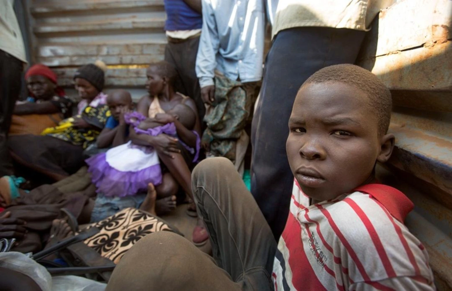 South Sudanese refugees travel in the back of a truck being transferred to a Ugandan refugee transit centre after crossing the border between South Sudan and Uganda